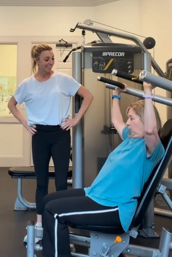 Robyn coaching a client through a seated shoulder press on a gym machine
