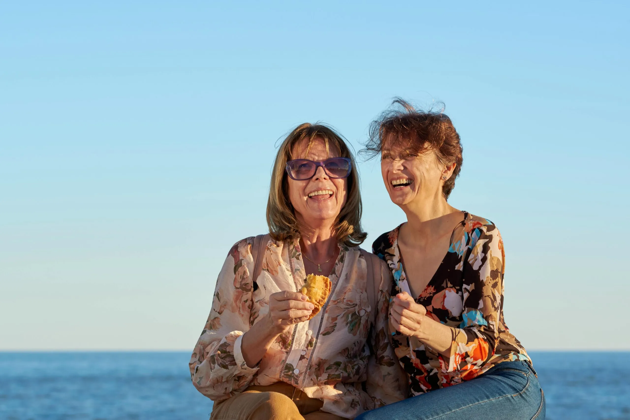 Two women laughing together by the sea