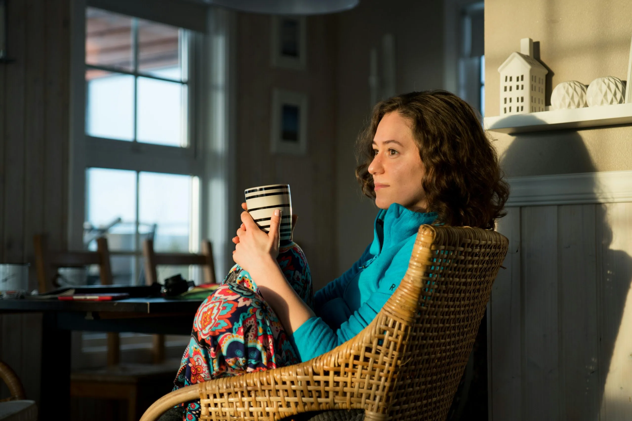 Woman relaxing in a wicker chair with a mug by the window