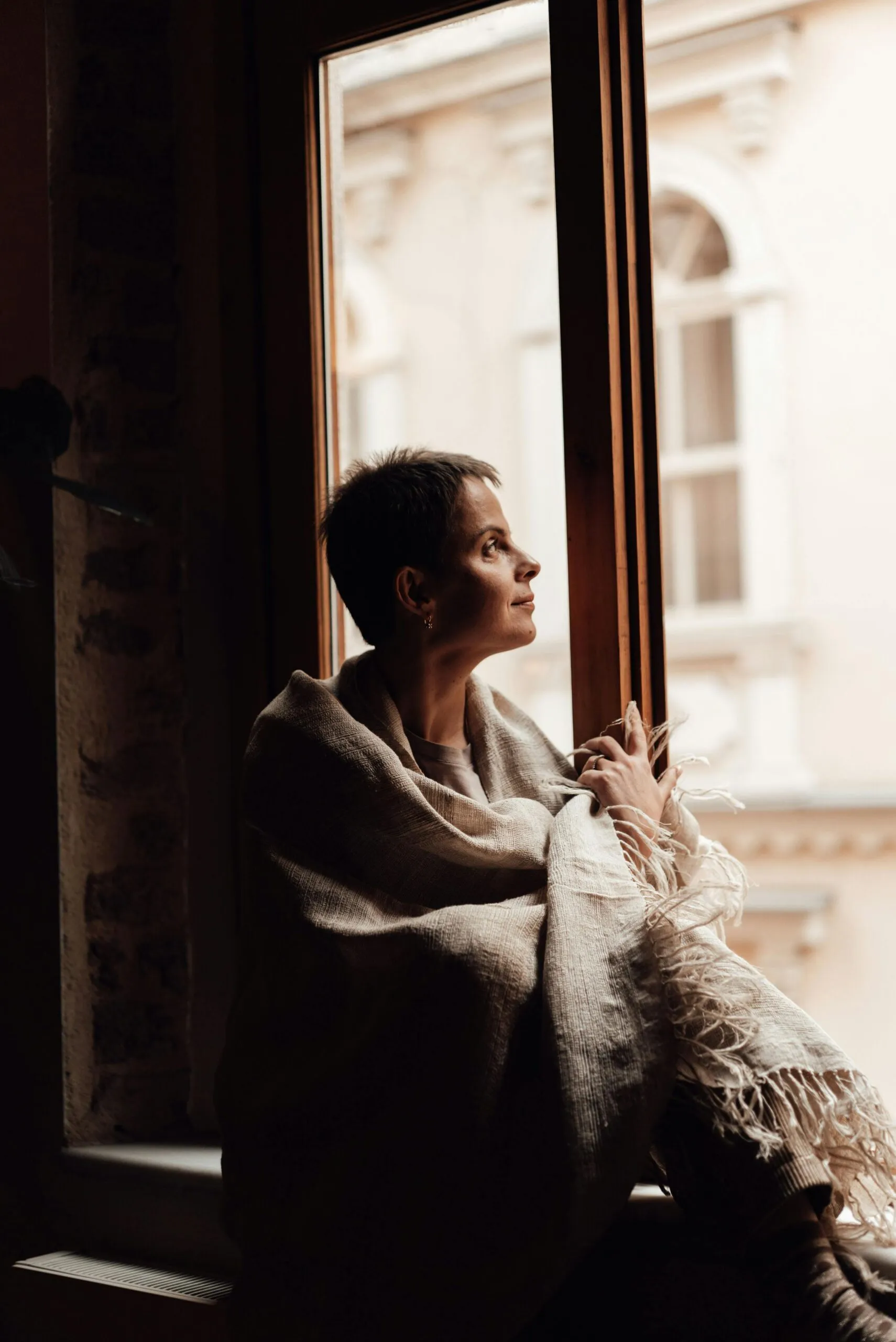 Woman resting by an open window in morning light